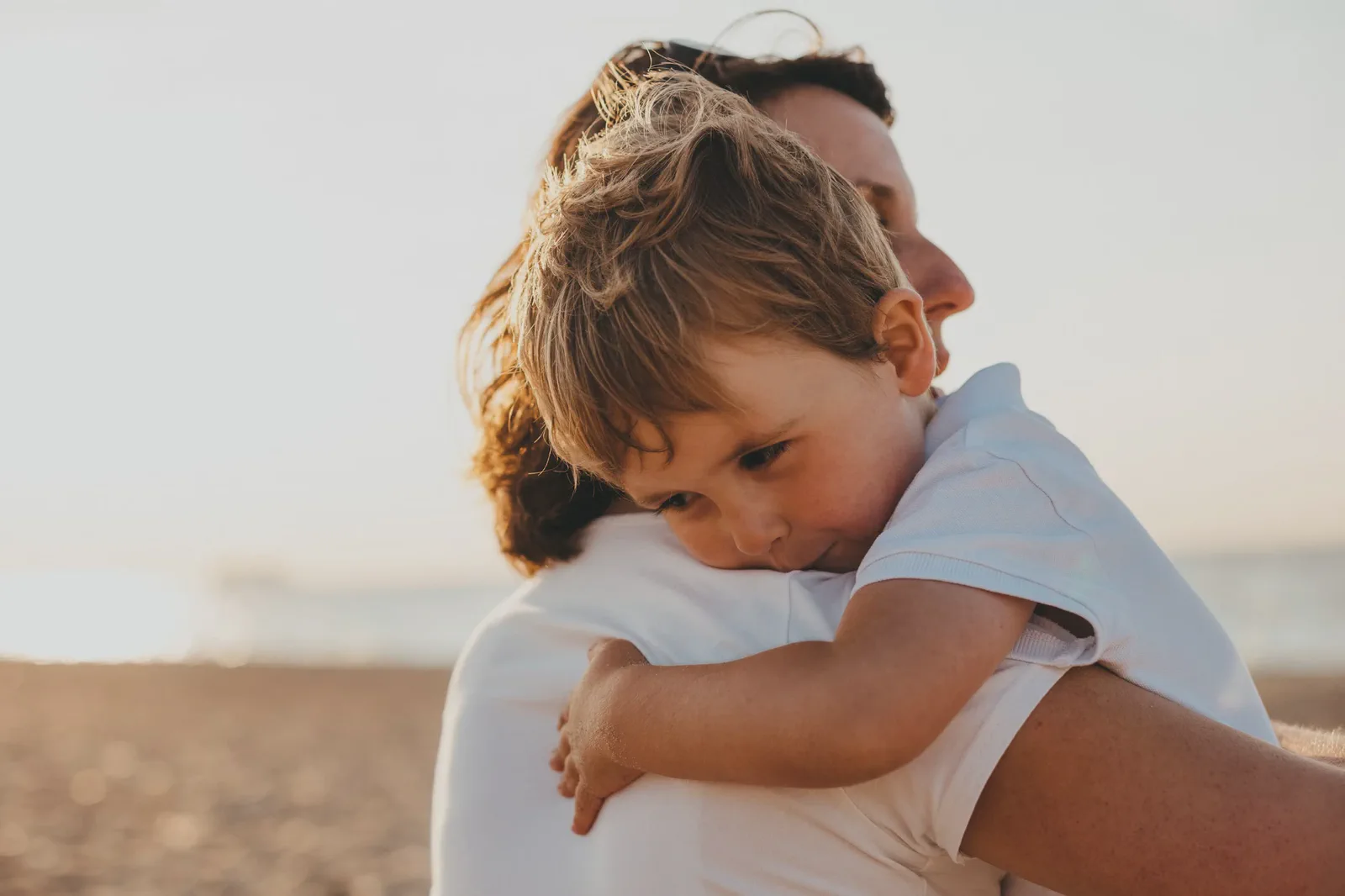 A parent holding their child close on the beach